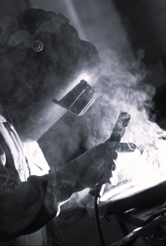 Image of worker welding with fumes visible.